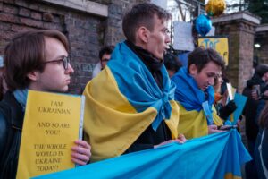 Image of protestors holding Ukrainian flag and a sign that says "I am Ukrainian. And so are you! The whole world is Ukraine today!"